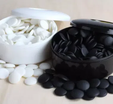 Pierres de go blanches et noires en résine dans leurs boîtiers ouverts