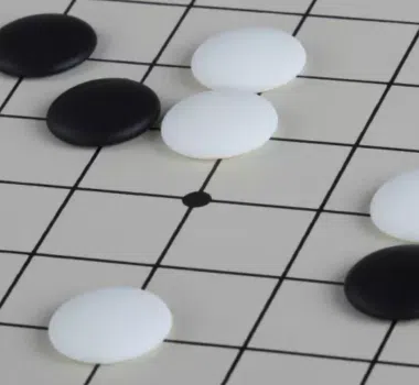 Pierres de go noires et blanches en résine disposées sur le goban