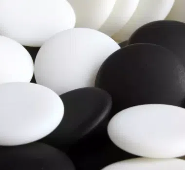 Gros plan sur des pierres de go blanches et noires mélangées